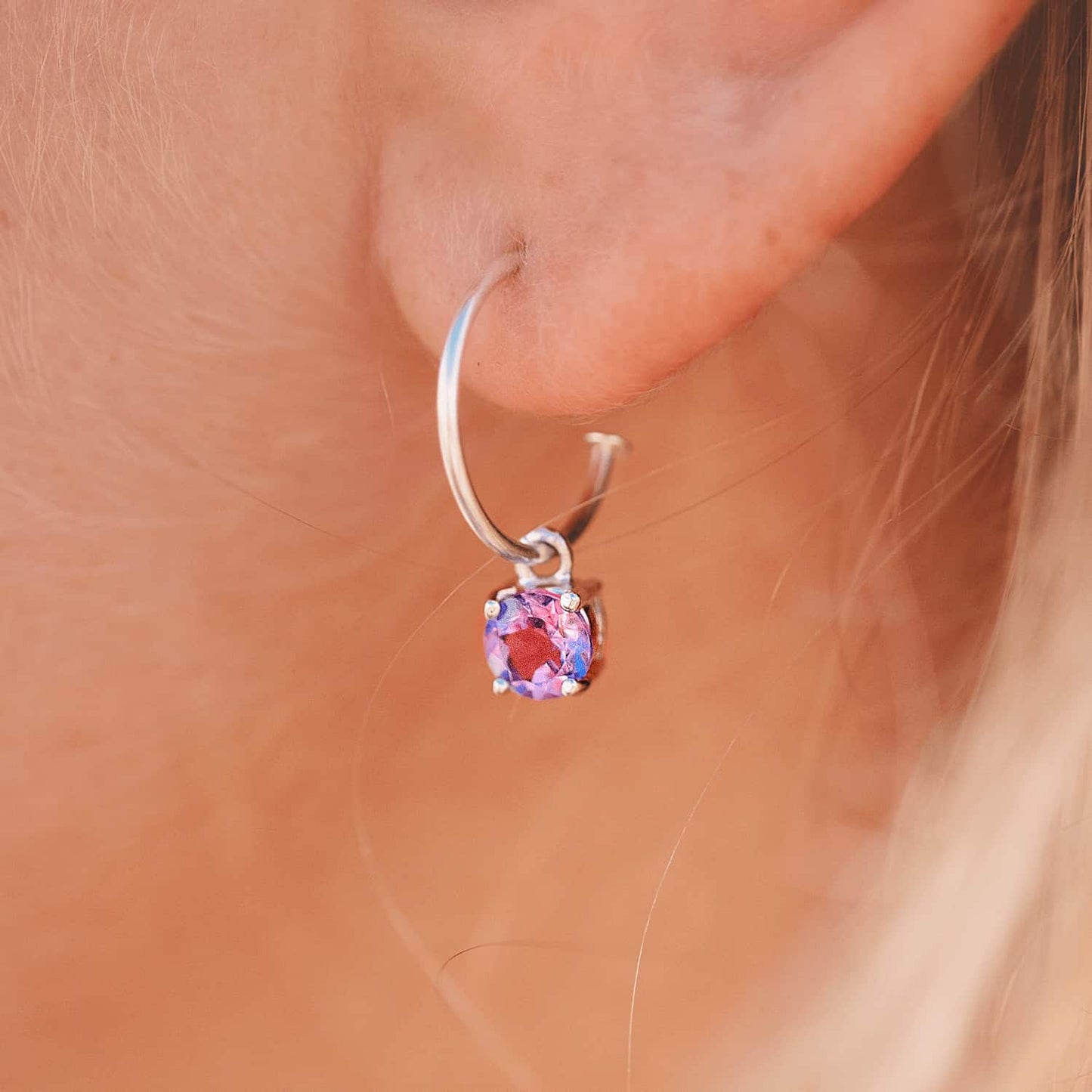 Side view of a woman wearing Amethyst Dangle Hoop earrings, showcasing a detachable 5mm round Amethyst gemstone set in four claws on a Sterling Silver hoop.