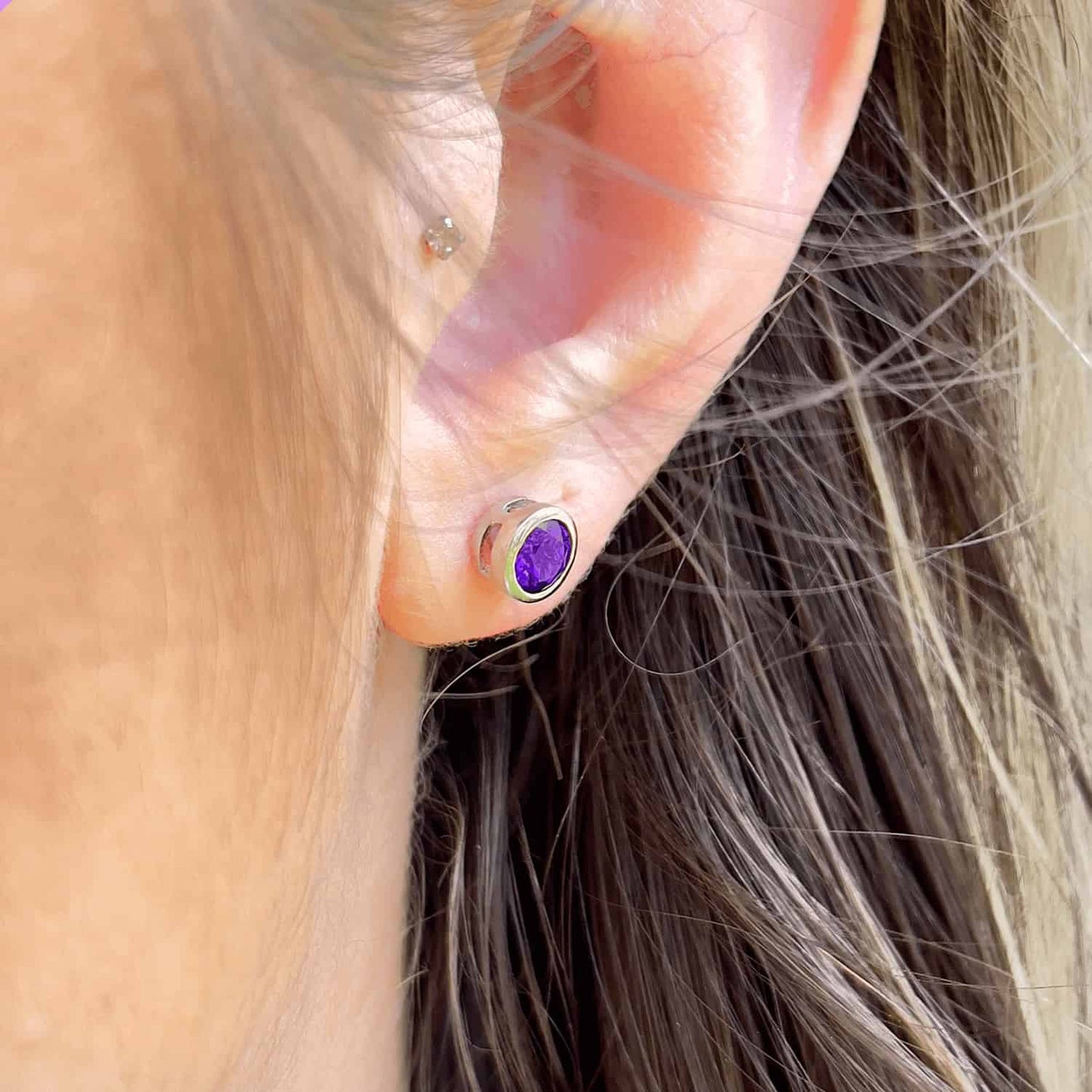 Close-up side view of a woman wearing the Amethyst tube set stud, showcasing a 5mm round Amethyst gemstone in a stirling silver tube setting.