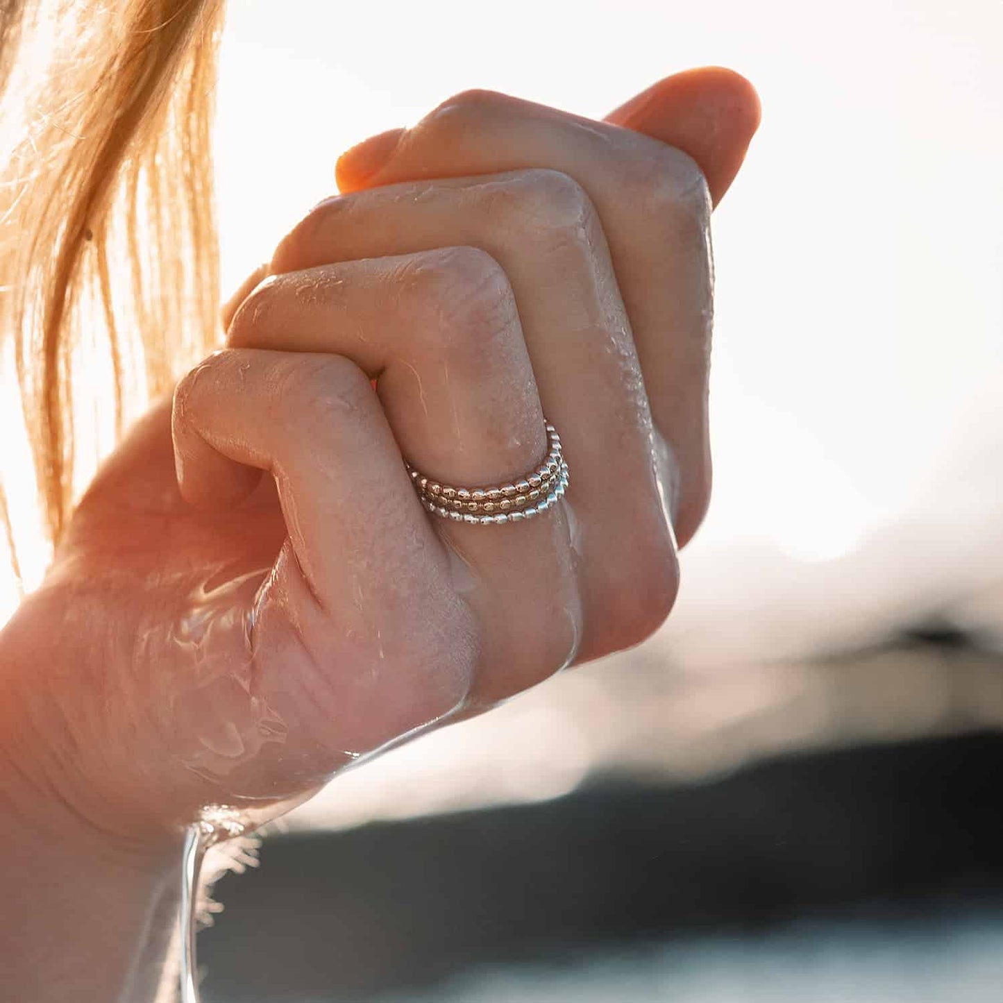 Woman's finger adorned with stacked Ball rings, including yellow and rose gold versions. Versatile Sterling Silver design for any style.