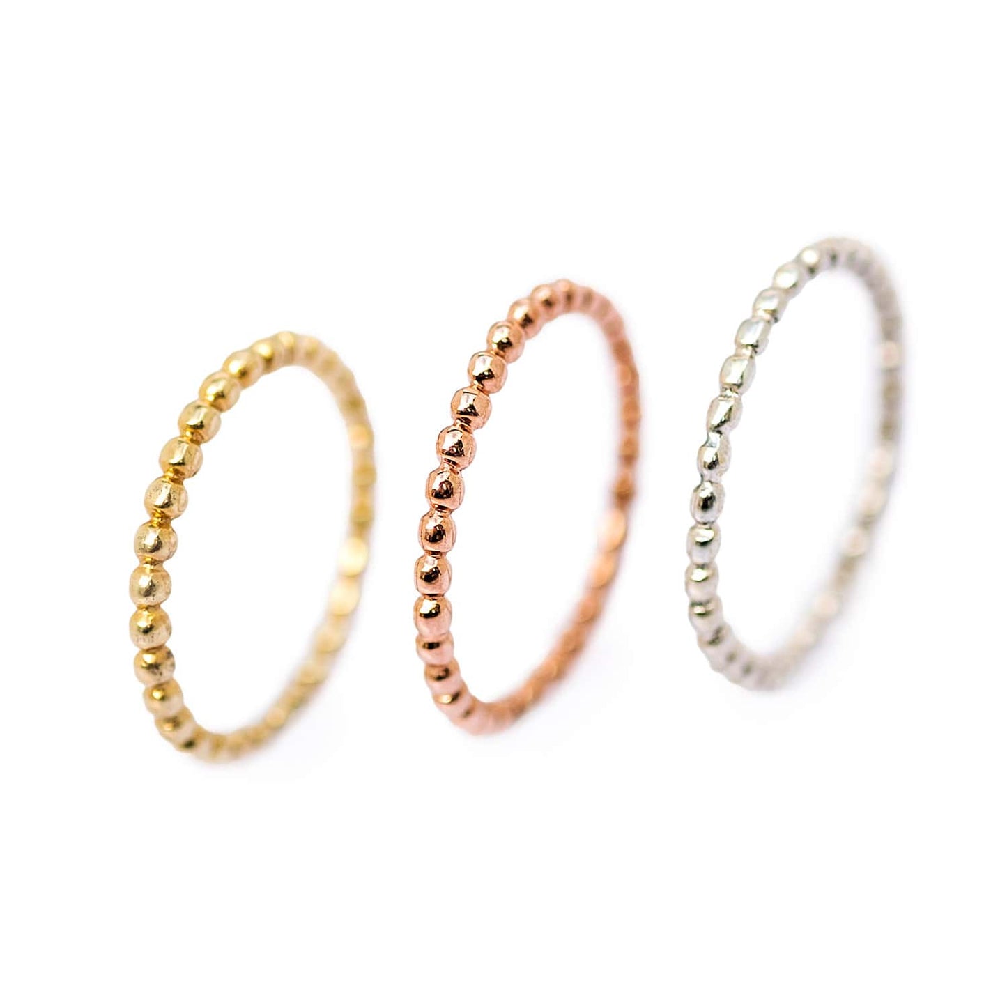 Sterling silver, yellow, and rose gold plated versions of the Ball ring standing side by side on a white background. Versatile and elegant jewelry for any occasion