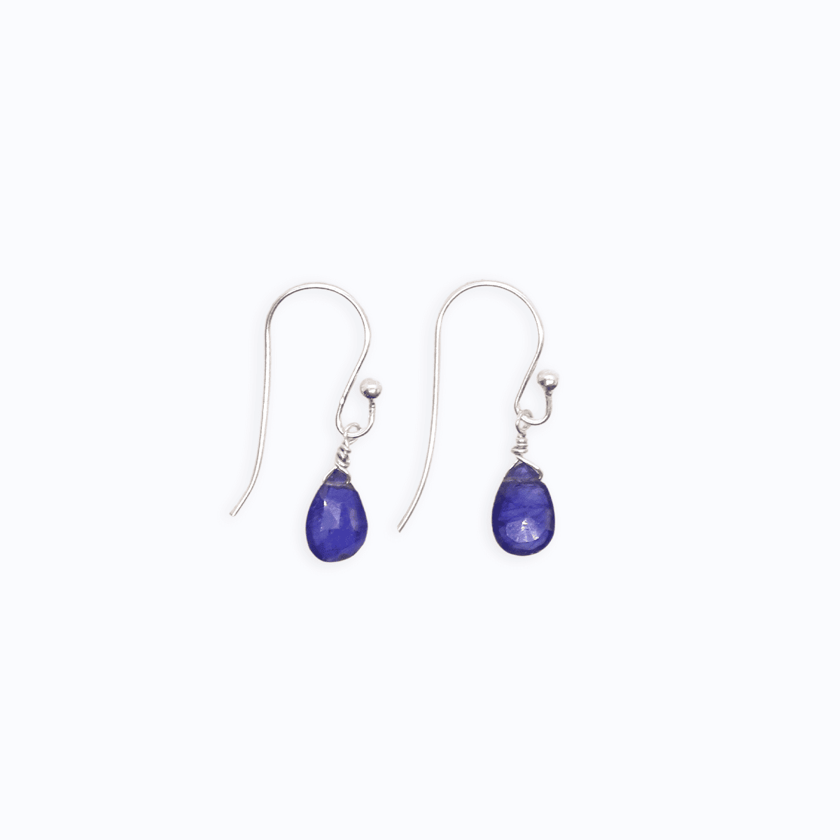 Flat lay view of Sterling Silver shepherd’s hook earrings with Sapphire drop next to each other on white background.