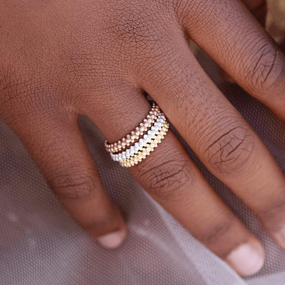 Close-up of woman's hand showcasing Bauble Ring in Sterling Silver, Rose Gold, and Yellow Gold plated options. Each ring consists of three rows of silver balls, with smaller ones on outer layers and slightly larger ones in the centre.