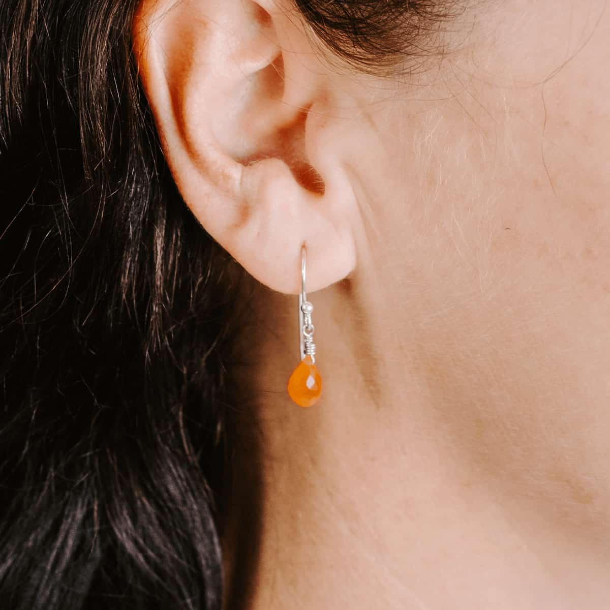 Close up front view of woman wearing Sterling Silver shepherd’s hook earring with Carnelian drop.