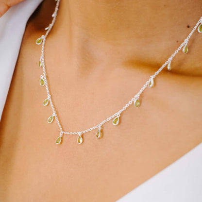 Side view of woman wearing Sterling Silver necklace with eighteen 5 x 3mm pear-shaped Peridot gemstones on 42cm chain.