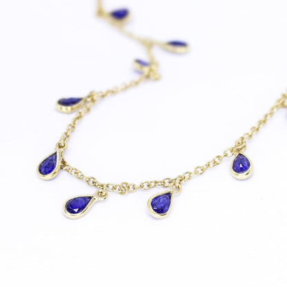 Flat lay view of Sterling Silver Yellow Gold plated necklace with eighteen 5 x 3mm pear-shaped Sapphire gemstones on 42cm chain, 5cm extension.