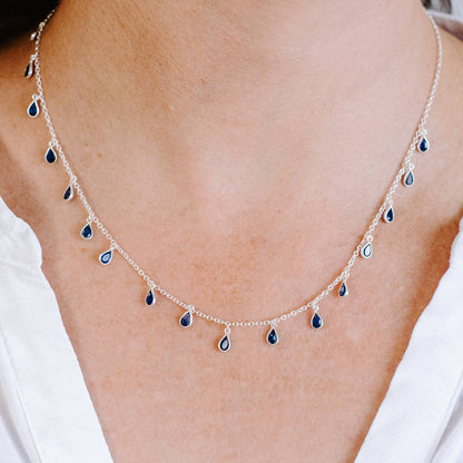 Close up front view of woman wearing Sterling Silver necklace with eighteen 5 x 3mm pear-shaped Sapphire gemstones on 42cm chain.