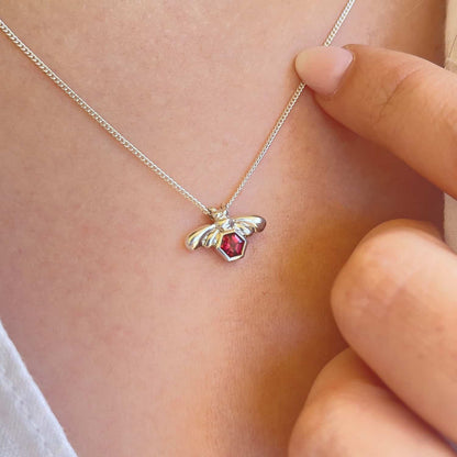 Close-up image of a woman wearing the Bee-YOU-tiful Bee Garnet Bling, showcasing a 45cm curb chain and a Sterling Silver pendant featuring a bee and a 4mm hexagonal Garnet gem set in its belly with a tube setting.