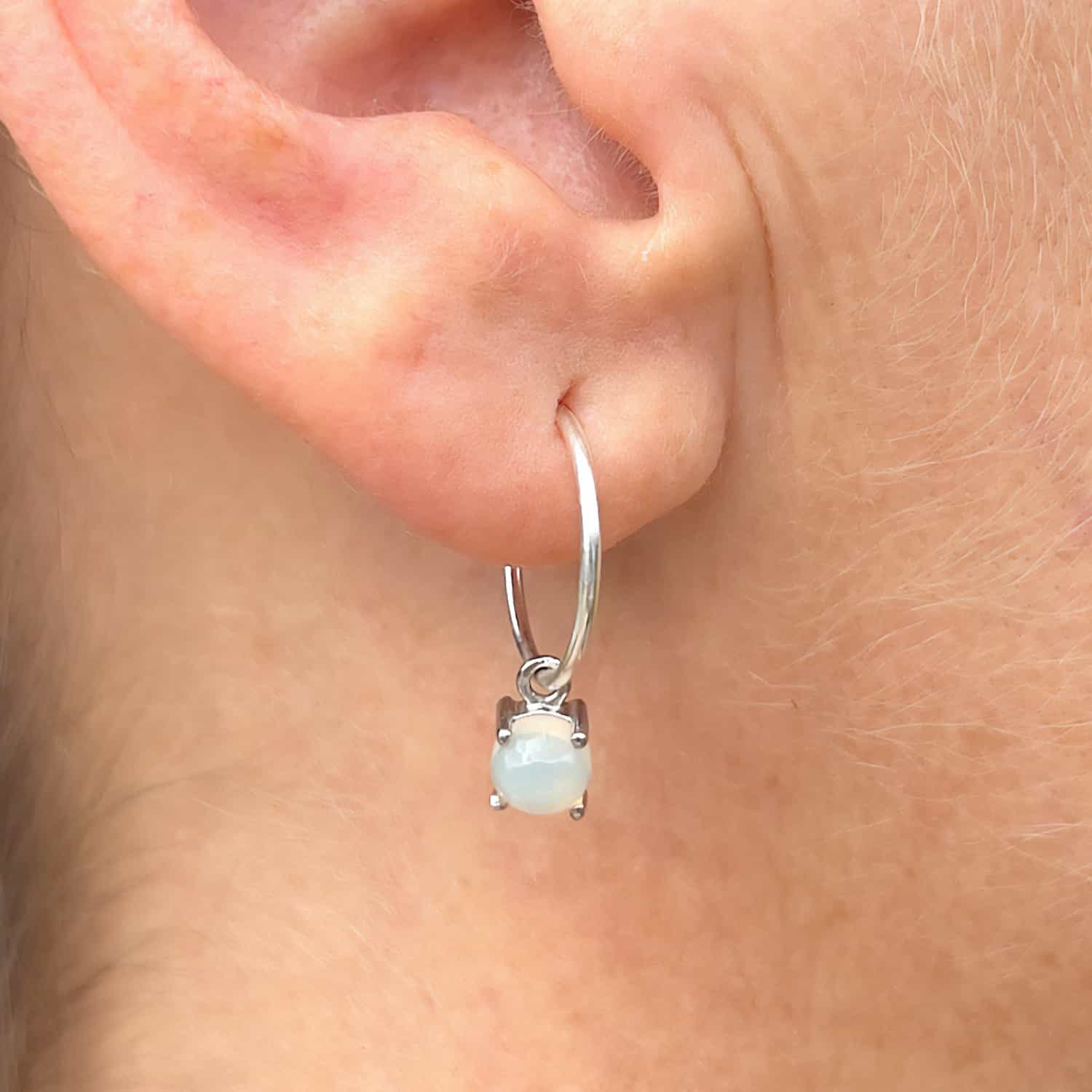 Front view of woman wearing Ethiopian Opal Dangle Hoop earrings, showcasing stunning opal gemstones in Sterling Silver