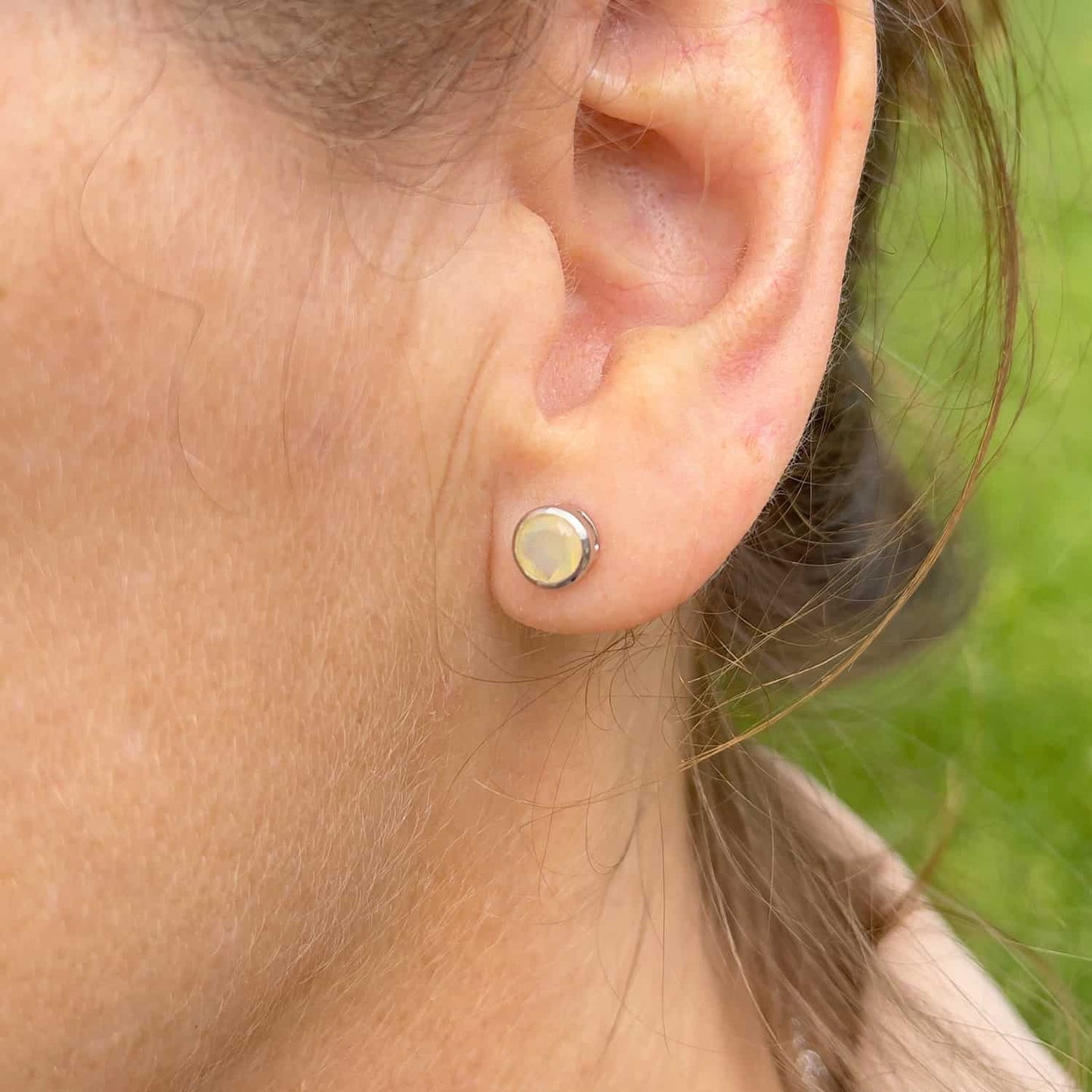 Close-up front view of a woman wearing the Ethiopian Opal Tube Set Studs, highlighting a 5mm round Ethiopian Opal gemstone set in sterling silver tube setting.