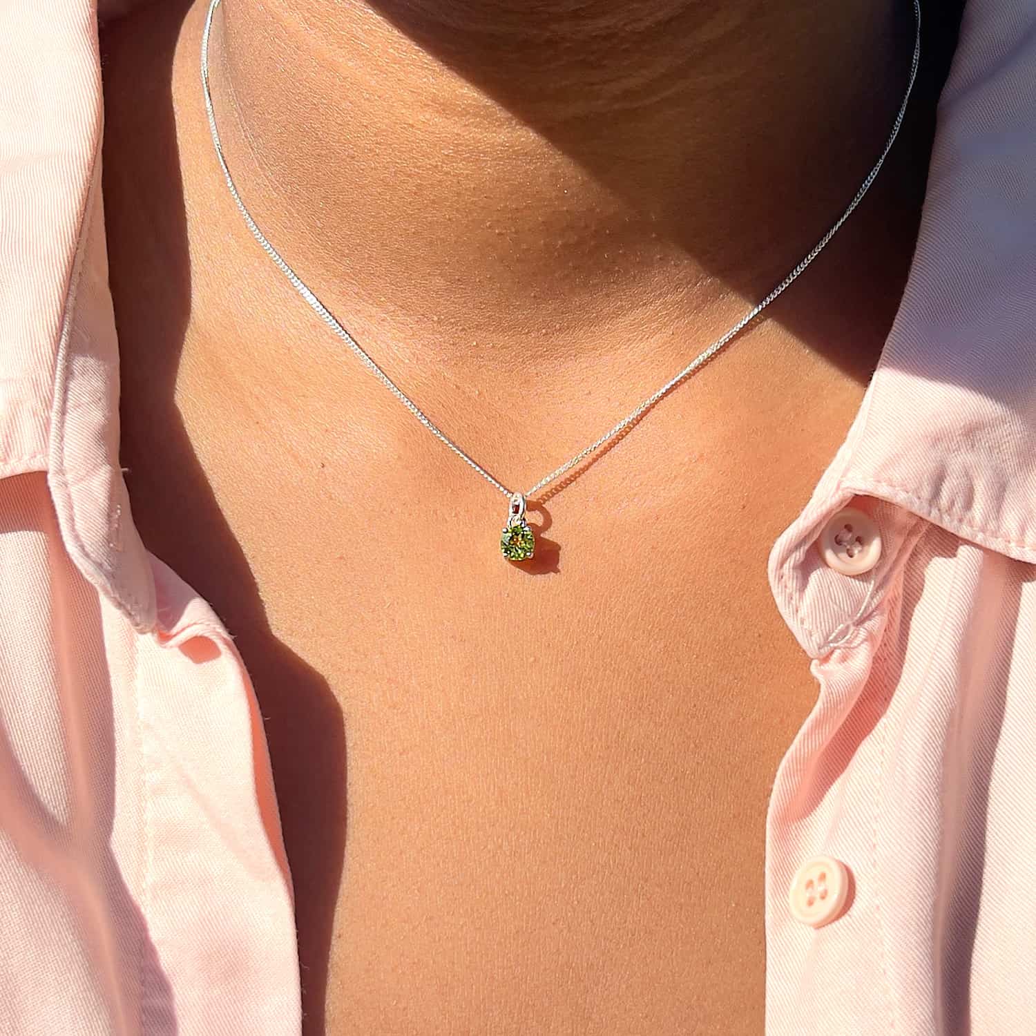 Woman wearing Peridot Pendant necklace, front view. 5mm round Peridot gemstone in four claws on 45cm curb chain.