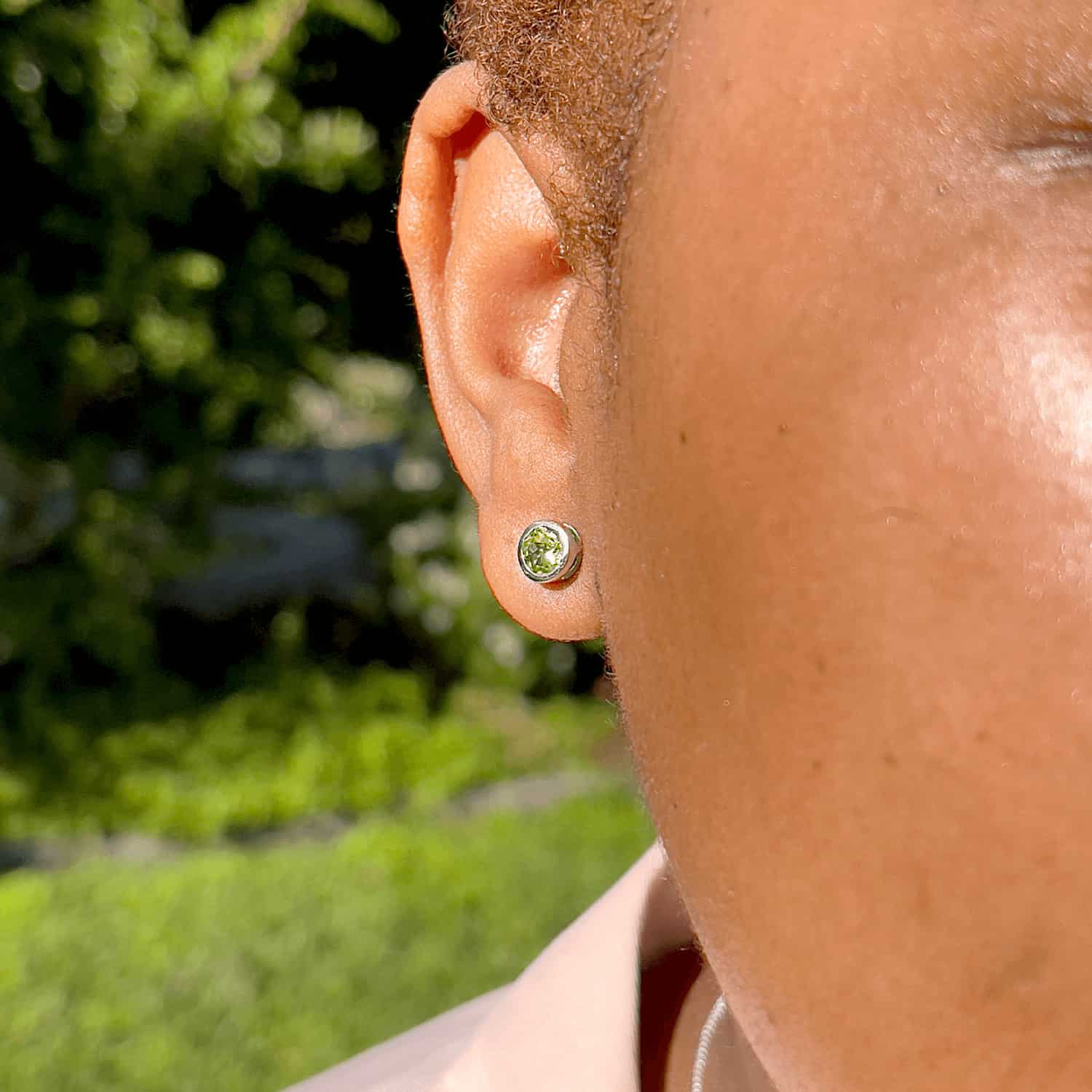 Woman wearing the Peridot Tube Set Studs, highlighting a 5mm round Peridot gemstone set in sterling silver tube setting.