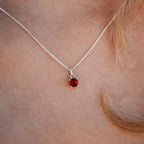 Woman wearing the Ruby Pendant necklace with a 5mm round Ruby gemstone set in four claws on a 45cm sterling silver curb chain.