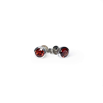 Front and side view of Garnet Tube Set Stud earrings on a white background. The earrings feature a 5mm round Garnet gemstone set in a Sterling Silver tube setting.