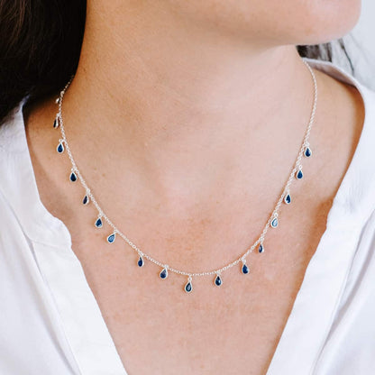 Front view of woman wearing Sterling Silver necklace with eighteen 5 x 3mm pear-shaped Sapphire gemstones on 42cm chain.