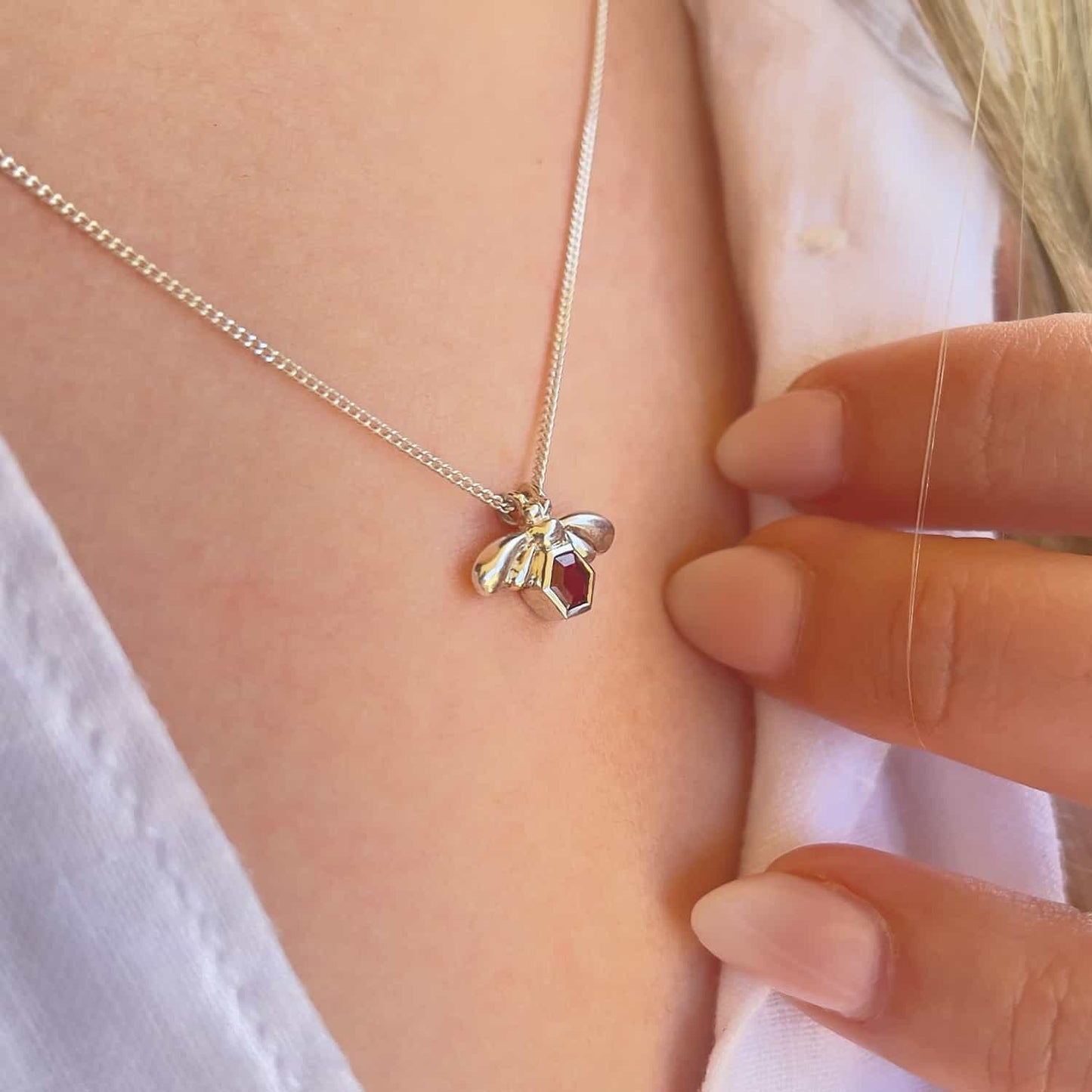 Close-up side view of a woman wearing the Bee-YOU-tiful Bee Garnet Bling, featuring a 45cm curb chain and a Sterling Silver pendant with a bee and a 4mm hexagonal Garnet set in its belly.