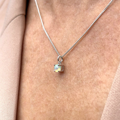 Side view of woman wearing Ethiopian Opal Pendant necklace. Features 5mm round Ethiopian Opal gemstone on 45cm curb chain.