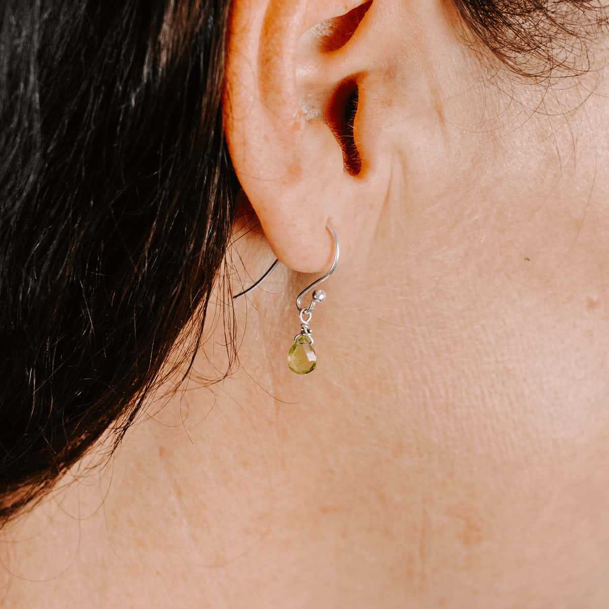 Woman wearing Sterling Silver shepherd’s hook earring with Peridot drop, side view.