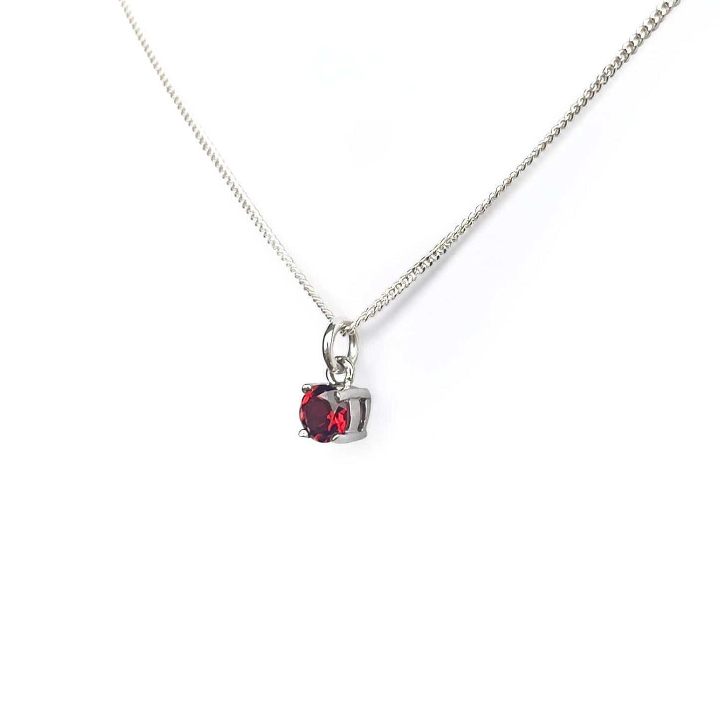 Close-up view of the Garnet Pendant Sterling Silver necklace on a white background. The necklace features a 5mm round Garnet gemstone set in four claws on a 45cm curb chain.