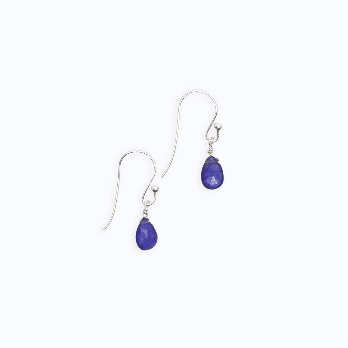 Flat lay view of two Sterling Silver shepherd’s hook earrings with Sapphire drop on white background.