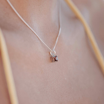 Woman wearing a Ruby Pendant necklace, showcasing a 5mm round Ruby gemstone set in four sterling silver claws on a 45cm curb chain.