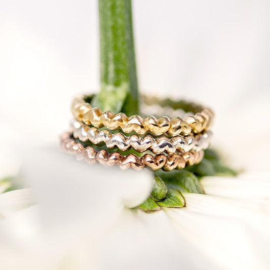 A Sterling Silver heart-shaped ring with multiple interlocking hearts forming a band, available in silver, yellow gold, and rose gold options