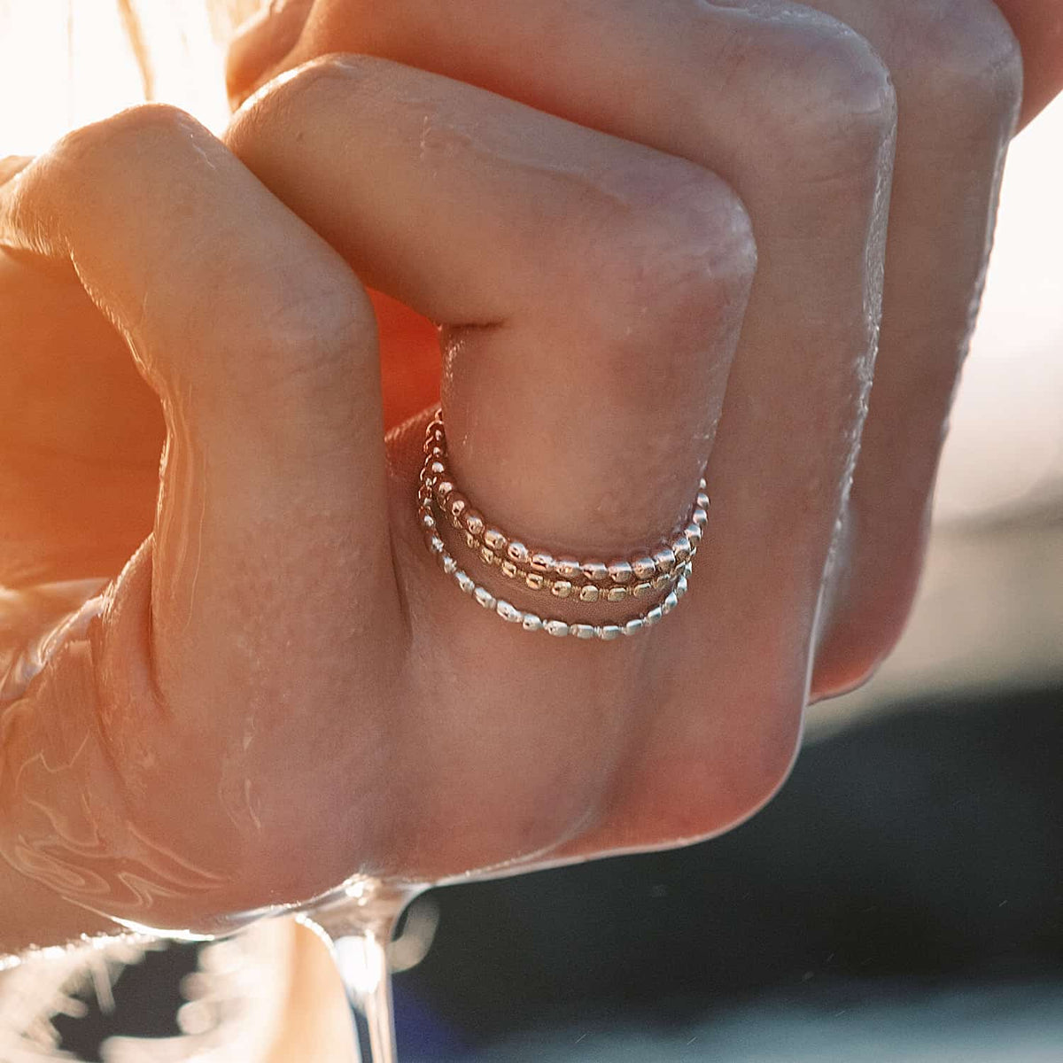 Woman's finger adorned with a stacked Ball ring, including yellow and rose gold versions. Versatile Sterling Silver design for any occasion.