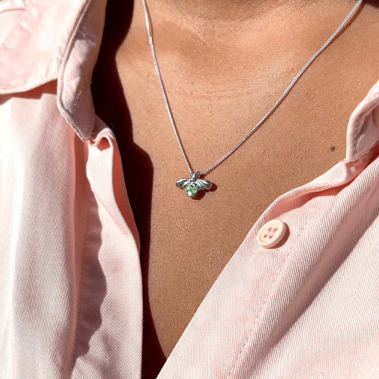 Woman wearing Bee-YOU-tiful Bee Peridot Bling necklace, side view. Sterling Silver bee pendant with 4mm hexagonal Peridot on 45cm curb chain.