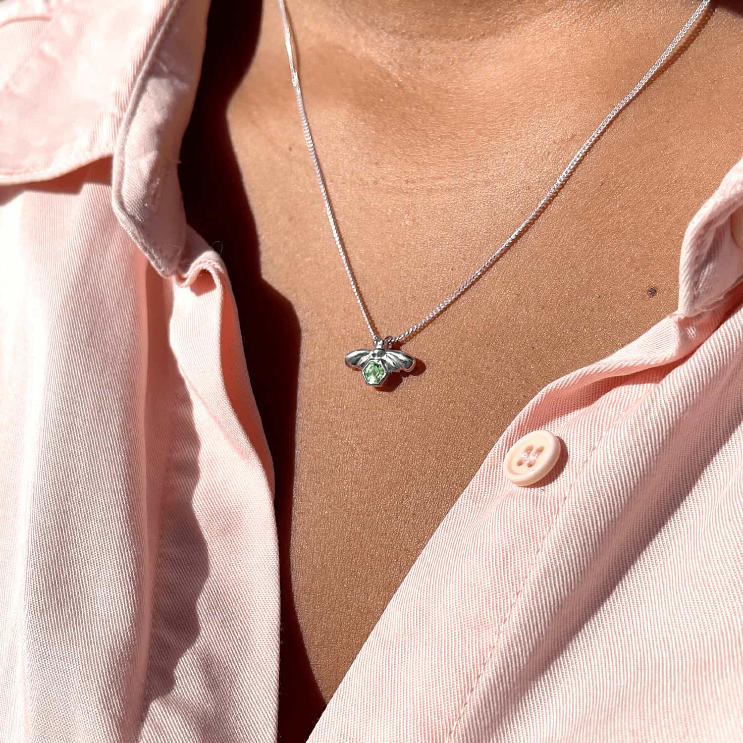 Woman wearing Bee-YOU-tiful Bee Peridot Bling necklace, side view. Sterling Silver bee pendant with 4mm hexagonal Peridot on 45cm curb chain.