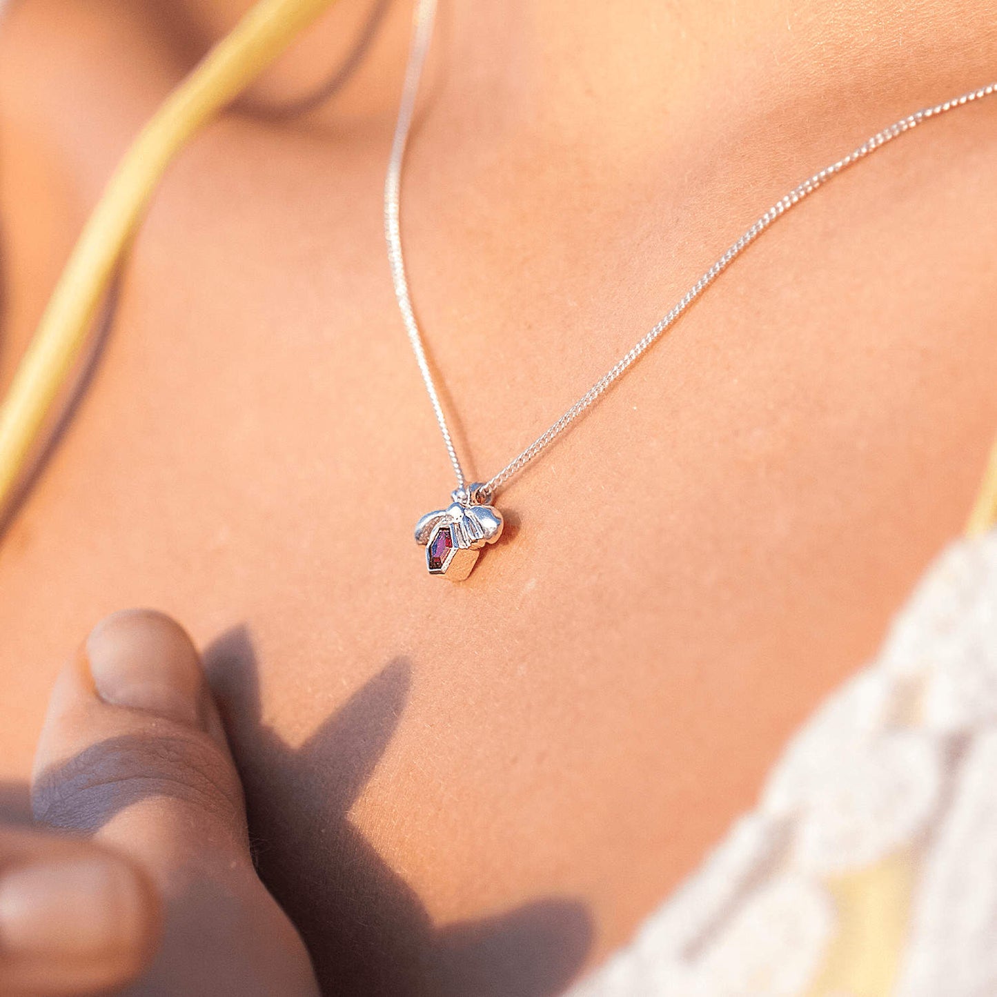 Side view of the Bee-YOU-tiful Bee Pink Tourmaline Bling around a woman's neck, featuring a 45cm curb chain and a Sterling Silver pendant with a bee and a 4mm hexagonal Pink Tourmaline set in its belly.