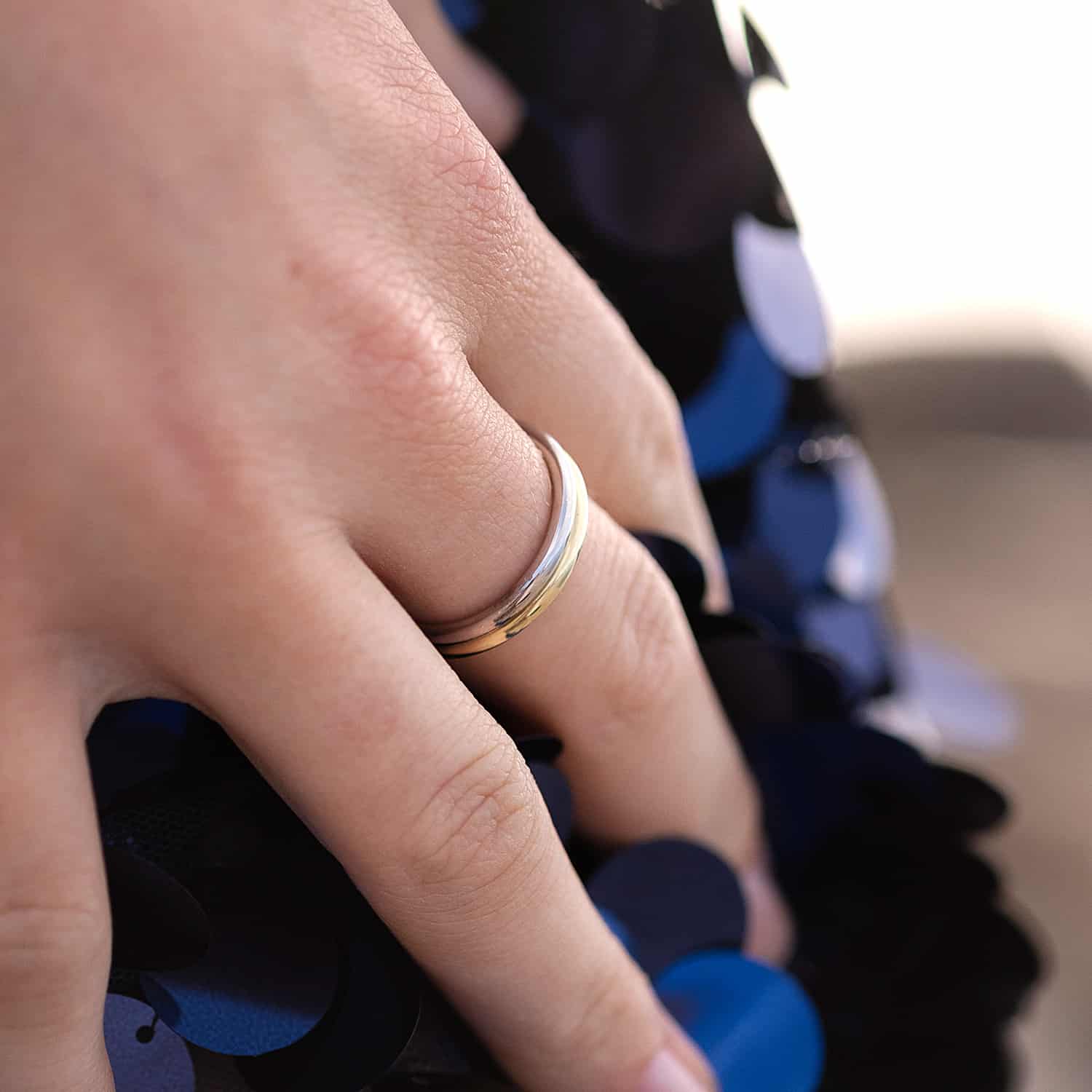 Woman's finger adorned with a Sterling Silver ring, accompanied by a yellow gold plated ring. The Sterling Silver bands are approximately 2mm wide, sleek, and polished.